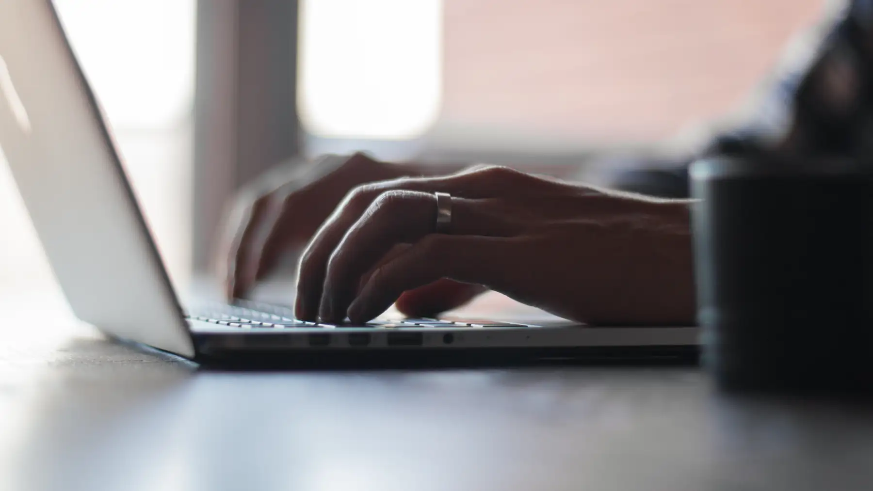 Hands typing on a laptop at a desk